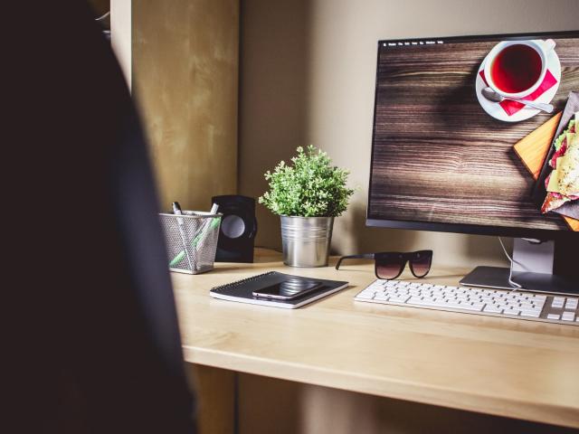 Tidy desk with a computer, plant and notebook